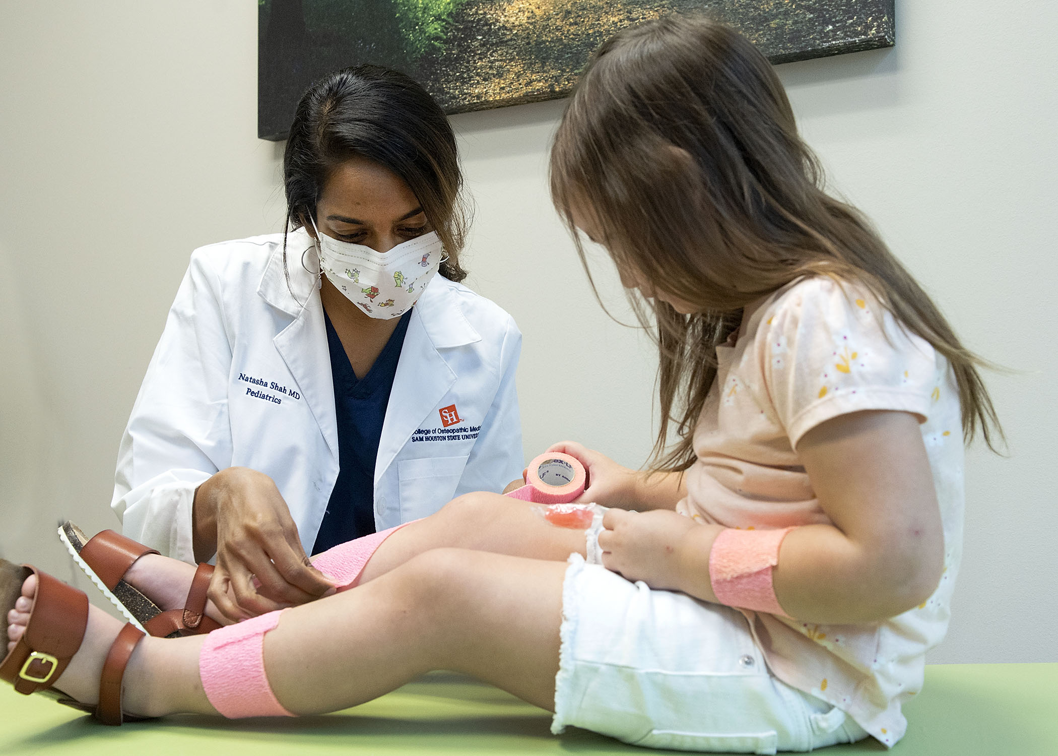 Physician making a pediatric patient comfortable at the doctor’s office during a checkup at SHSU Physicians